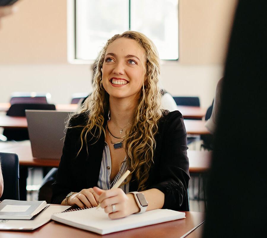 Creative writing student writes in a notebook in a classroom.